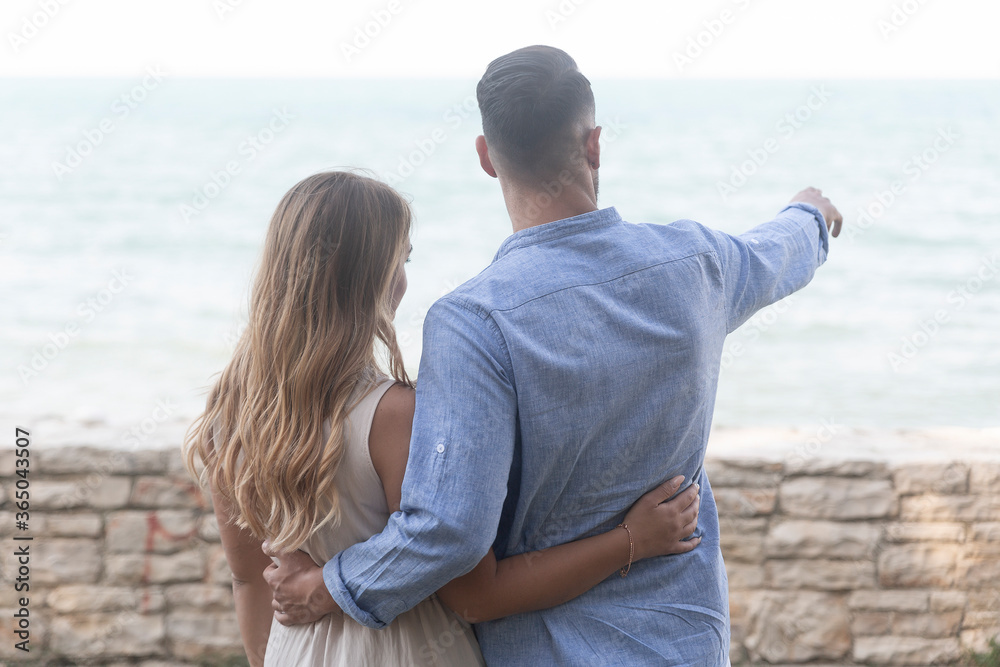 A romantic scene with happy spouses in a loving embrace as they look at the horizon almost at sunset