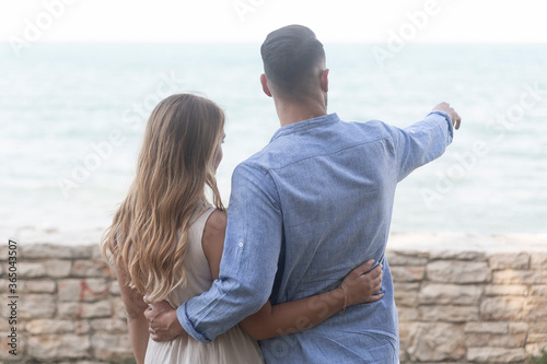 A romantic scene with happy spouses in a loving embrace as they look at the horizon almost at sunset