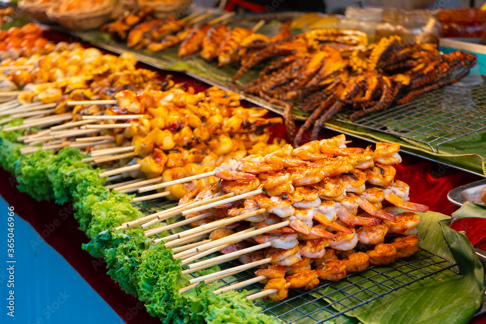 Street food market in Asia. Food counters, mini barbecue on a stick also called satey.