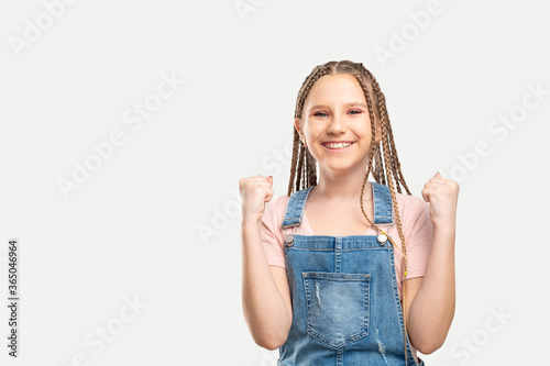 Excited kid portrait. Child success. Happy girl enjoying victory with yes gesture smiling isolated on white copy space.