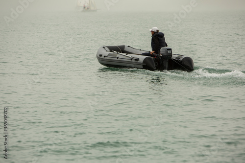 man in an inflatable boat floats on water in foggy weather