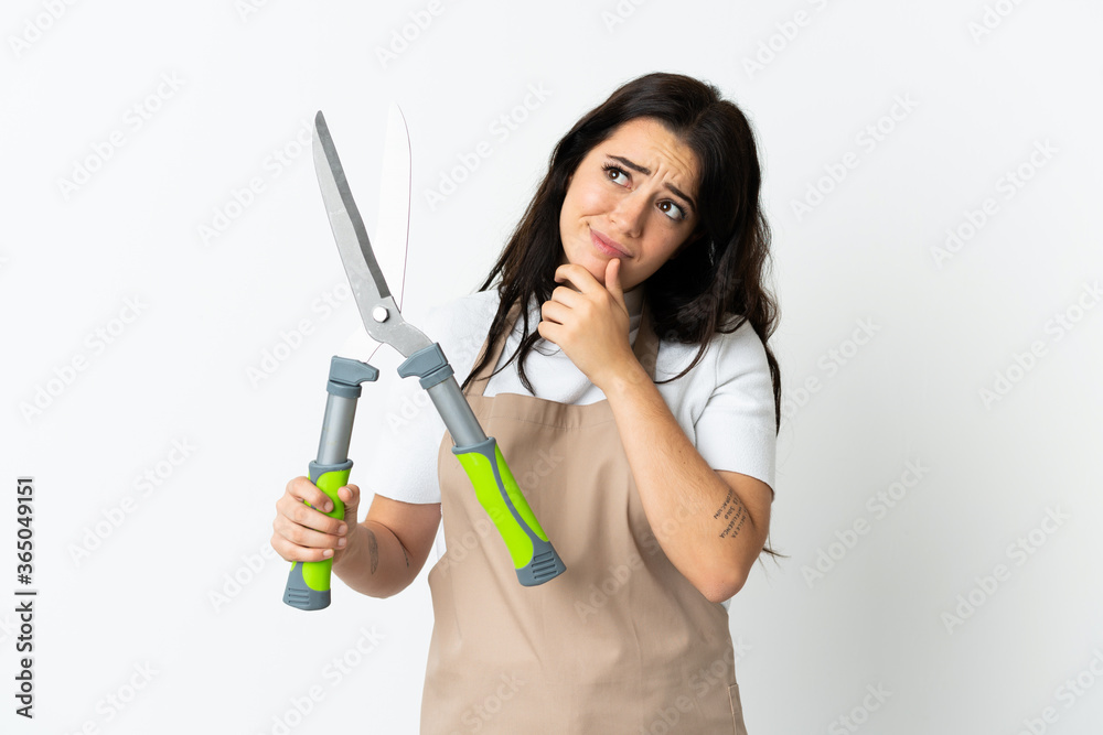 Young caucasian woman holding a plant isolated on white background having doubts Young caucasian woman holding a plant isolated on white background having doubts
