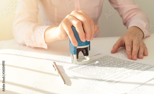 Photography Young businesswoman or notary public sitting at the desk in office and stamping