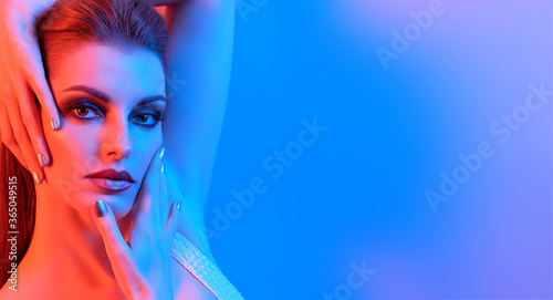High Fashion. Woman in colorful blue neon light, make-up. Sexy girl, stylish hair, trendy makeup. Party disco neon style. Creative art beauty portrait, fashionable model face, bright make up