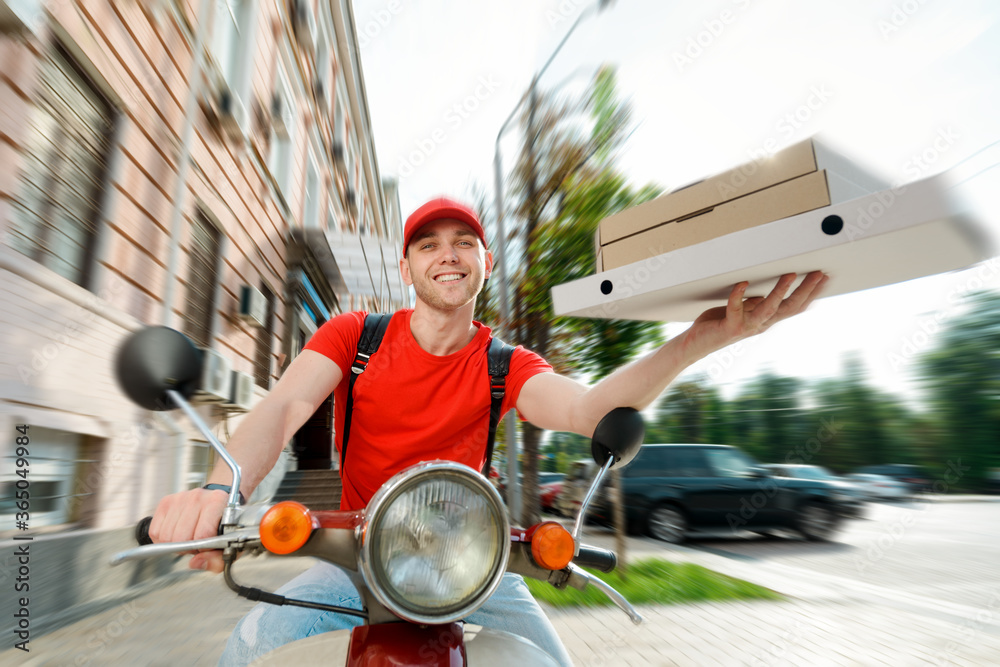 Young guy delivers pizza. The deliveryman is holding few paper boxes