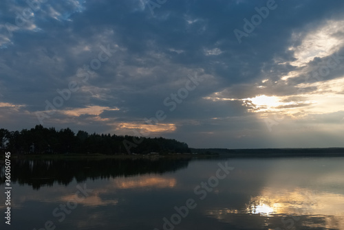 Summer sunset lake landscape with reflections on water surface.