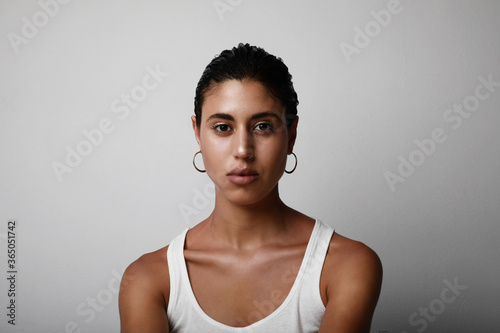 Brown skinned young woman proudly shows off her skin while posing over white background.