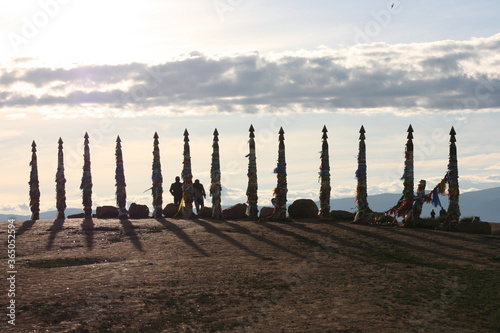  Olkhon / Russia - 27 June 2019: Shaman rock at lake Baikal with the sunset light. The bars of the hitching post tied with ribbons on Olkhon island. Beautiful summer landscape.