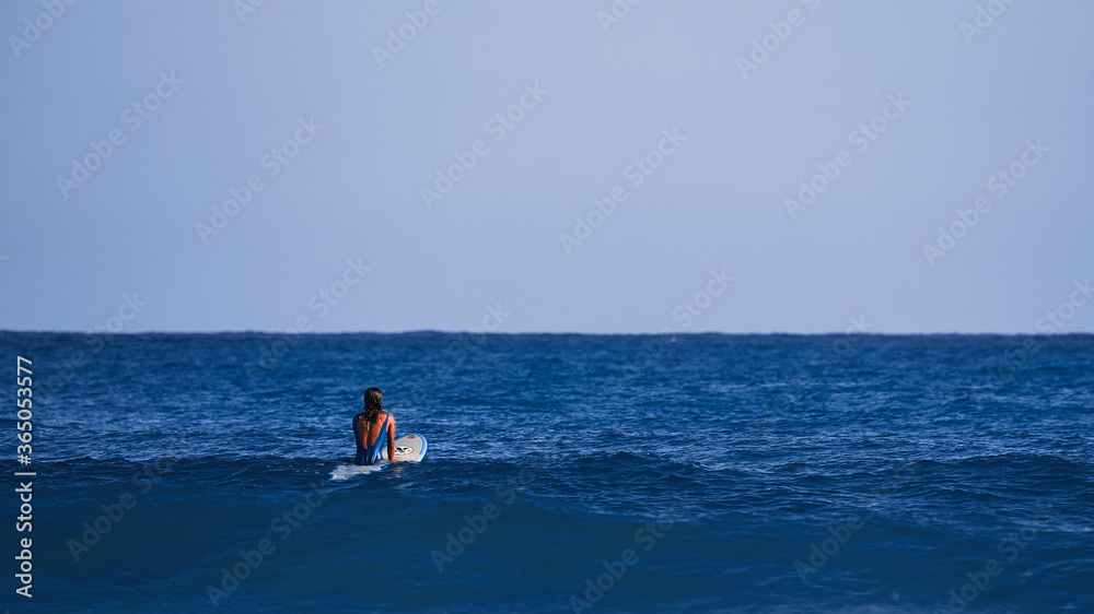 Obraz premium Surfer girl waiting for a wave. Surfer school. Beautiful young woman in swimsuit goes into ocean in hot summer day. Surfer on the wave. beautiful ocean wave. Water sport activity