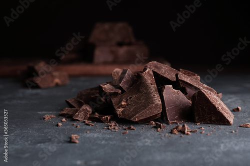 Pieces of tasty dark chocolate on grey table, closeup
