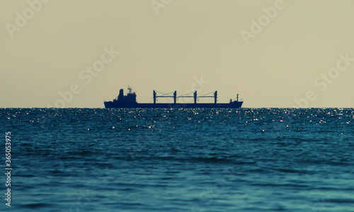 The silhouette of the cargo ship on the sea