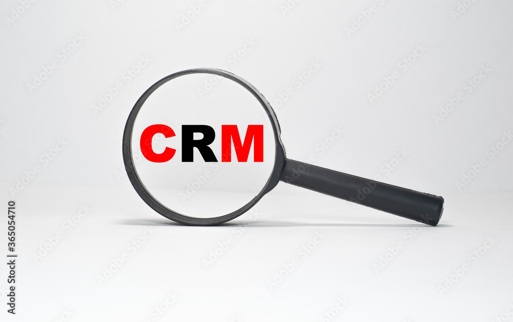 Red and black CRM inscription in a black magnifier on a white endless background Red and black CRM inscription in a black magnifier on a white endless background