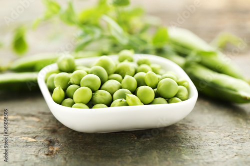 Green peas in bowl on wooden table