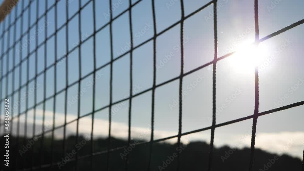 Volleyball net in the sand background close-up. The beach volleyball court is closed by the coronavirus. Sunset through the volleyball net Volleyball net in the sand background close-up. The beach volleyball court is closed by the coronavirus. Sunset through the volleyball net
