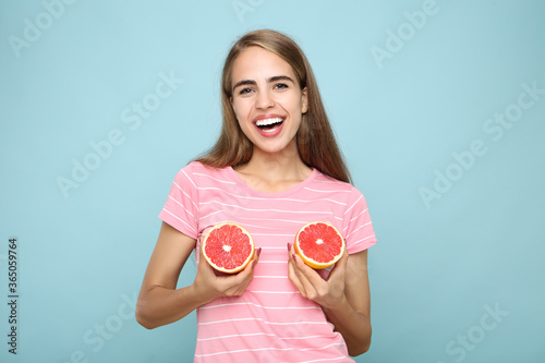 Young girl with fresh grapefruit on blue background