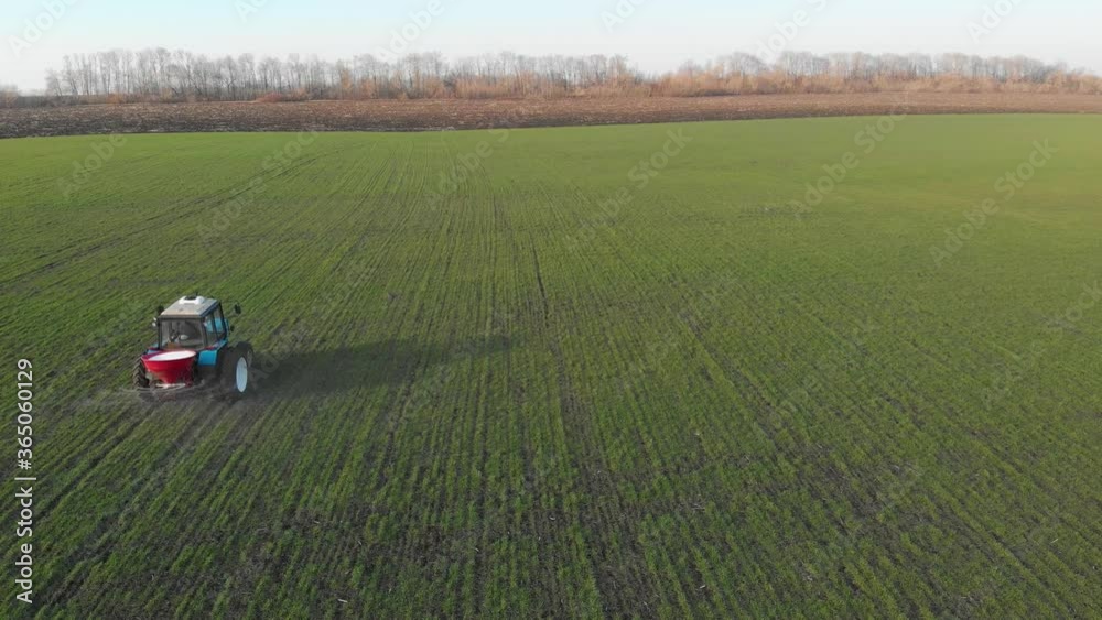 Tractor spreading artificial fertilizers in green field. Farmer fertilizing arable land with nitrogen and potassium fertilizer. Tractor spreading artificial fertilizers in green field. Farmer fertilizing arable land with nitrogen and potassium fertilizer.
