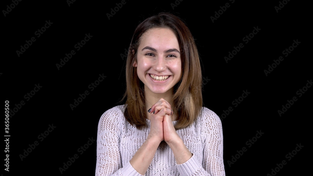 The young woman shows emotions of joy. Woman enthusiastically smiles on a black background The young woman shows emotions of joy. Woman enthusiastically smiles on a black background