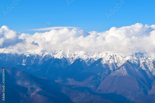 Cumulus clouds flying over a mountain range. © Kseniia