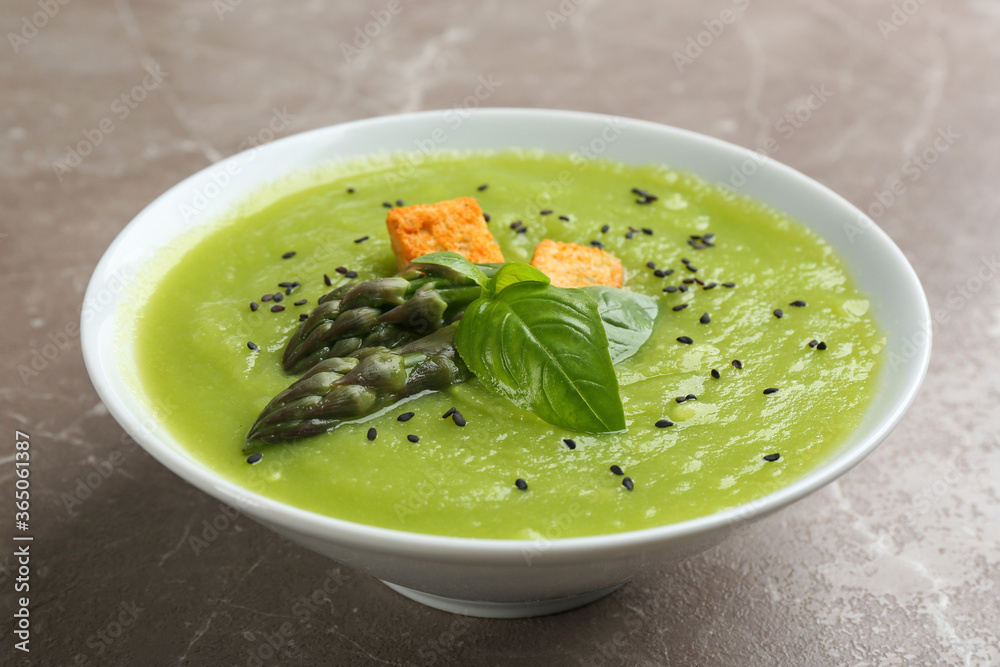 Delicious asparagus soup in bowl on grey marble table Delicious asparagus soup in bowl on grey marble table