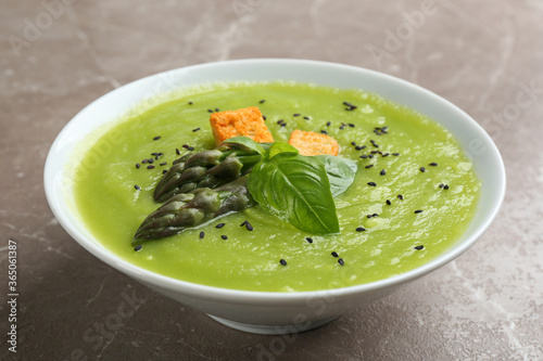 Delicious asparagus soup in bowl on grey marble table