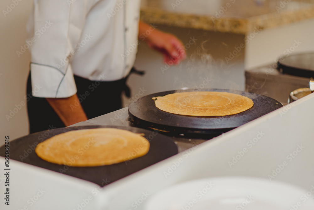 pessoa vestindo doma e avental preto de frente ao buffet com 2 crepes quentes pessoa vestindo doma e avental preto de frente ao buffet com 2 crepes quentes