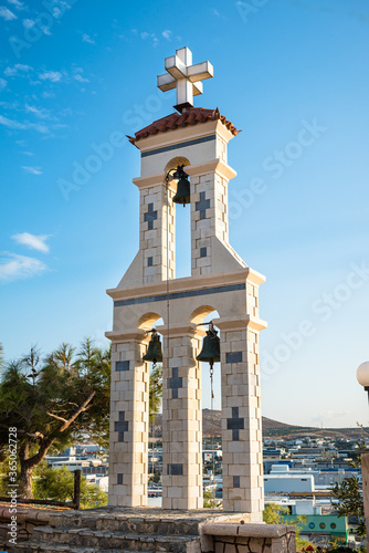 Stone construction with three church bells and with a greek orthodox cross on top.