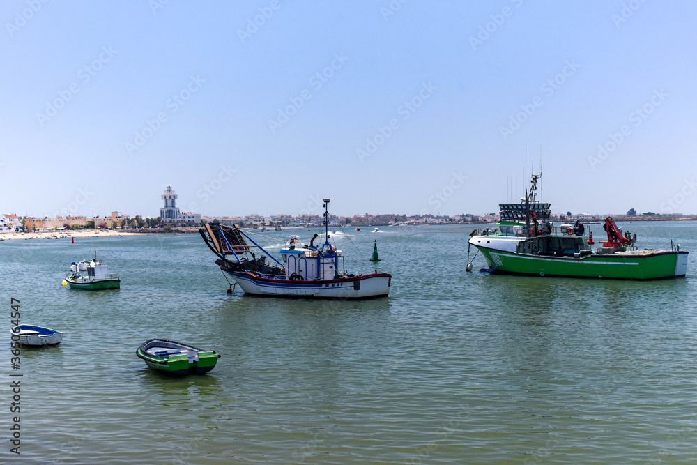 View of Isla Cristina from the port with fishing boats and the lighthouse in the background on a clear and sunny day. Isla Cristina, Huelva, Andalusia, Spain View of Isla Cristina from the port with fishing boats and the lighthouse in the background on a clear and sunny day. Isla Cristina, Huelva, Andalusia, Spain