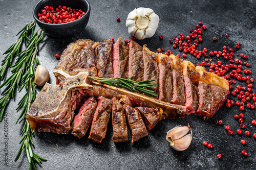 Sliced Grilled T-bone steak. Cooked tbone beef meat. Black background. Top view