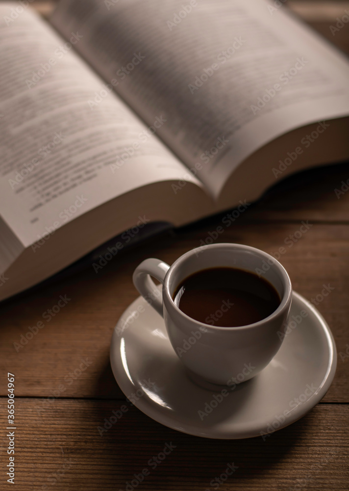 Cup of coffee and a book on a wooden table Cup of coffee and a book on a wooden table