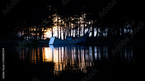 the fir silhouette when sunset over the river and fishing boat