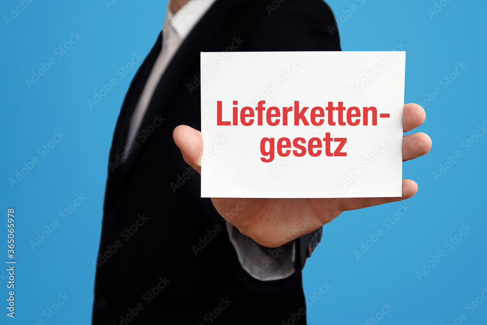 Lieferkettengesetz. Geschäftsmann im Anzug hält Karte in die Kamera. Der Begriff Lieferkettengesetz steht im Schild. Symbol für Business, Finanzen, Statistik, Analyse, Wirtschaft Lieferkettengesetz. Geschäftsmann im Anzug hält Karte in die Kamera. Der Begriff Lieferkettengesetz steht im Schild. Symbol für Business, Finanzen, Statistik, Analyse, Wirtschaft