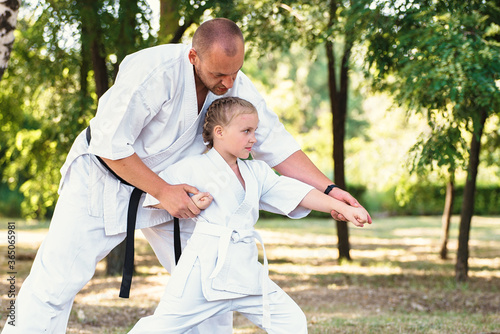 Karate instructor, sensei teaches a child a girl martial arts