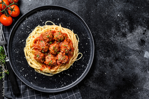 Spaghetti pasta with meatballs and tomato sauce. Italian cuisine. Black background. Top view. Copy space