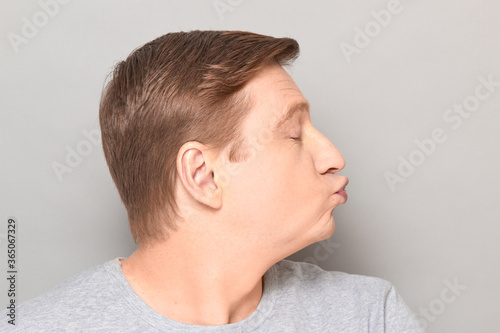 Portrait of funny mature man pouting his lips and blowing kiss