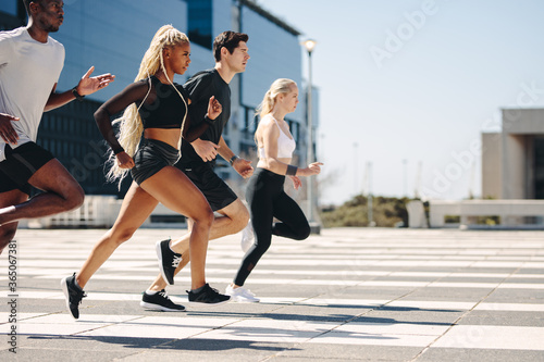 Multi-ethnic group of people running together in the city
