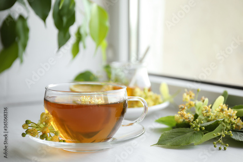 Cup of tea with linden blossom on white windowsill
