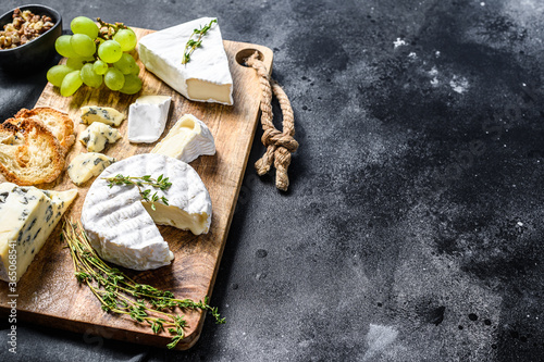 Cheese Board with French Camembert, brie and blue cheese, grapes and walnuts. Black background. Top view. Copy space