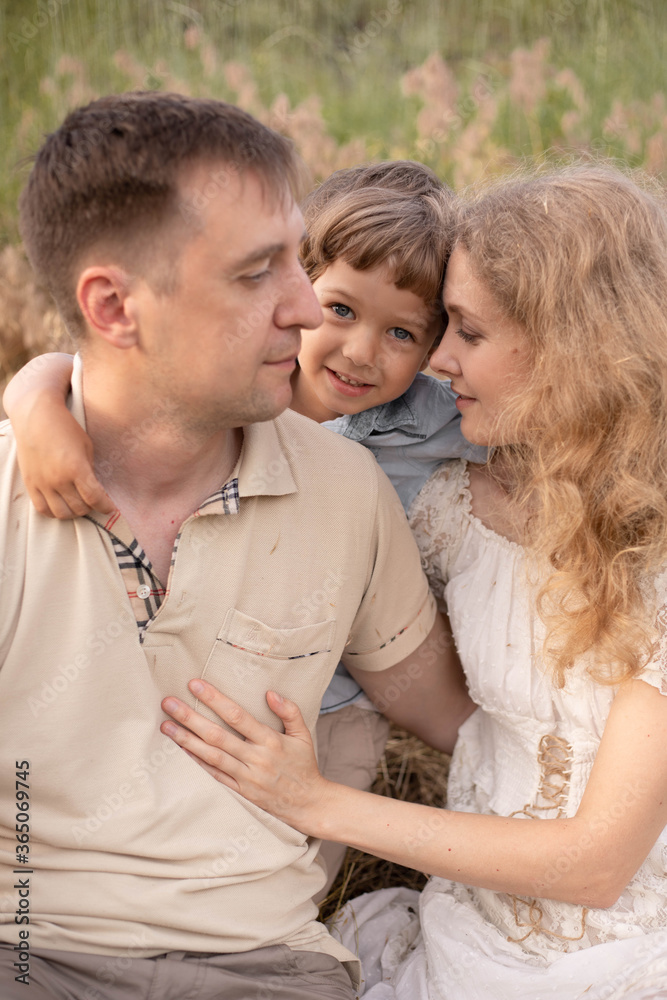 Happy family, cuddling in the field, mom and dad love their son, baby with golden hair, blonde woman, beautiful people, games with parents, bright children Happy family, cuddling in the field, mom and dad love their son, baby with golden hair, blonde woman, beautiful people, games with parents, bright children