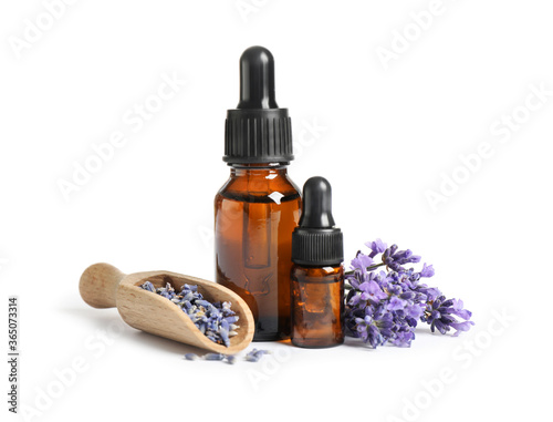Bottles of essential oil and lavender flowers on white background