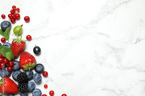 Mix of fresh berries on white marble table  flat lay. Space for text