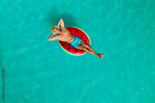 Happy man with inflatable ring in swimming pool, top view. Summer vacation © New Africa