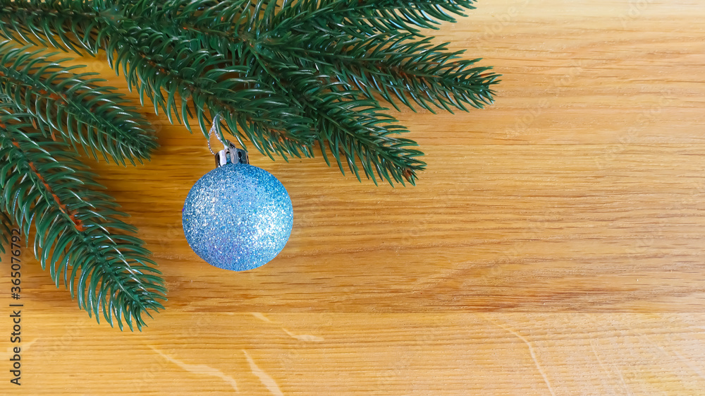 Christmas spruce branch and blue toy ball on a natural wooden background with space for text copy space flat Christmas spruce branch and blue toy ball on a natural wooden background with space for text copy space flat
