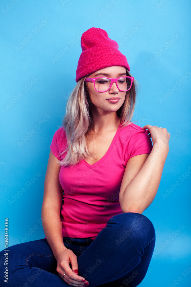 young pretty teenage modern hipster girl posing emotional happy on blue background, wearing pink hat and glasses, lifestyle people concept young pretty teenage modern hipster girl posing emotional happy on blue background, wearing pink hat and glasses, lifestyle people concept