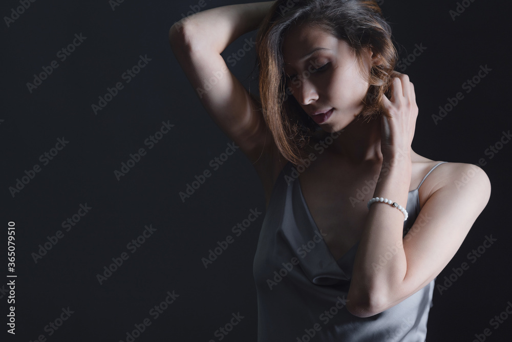 Portrait of a beautiful young girl on a dark background in a gray silk dress. The concept of beauty, youth and naturalness Portrait of a beautiful young girl on a dark background in a gray silk dress. The concept of beauty, youth and naturalness