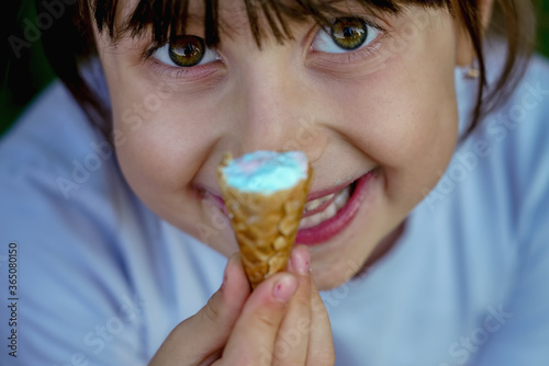 Top view of beautiful young child girl eating ice cream. Selective focus on eyes.