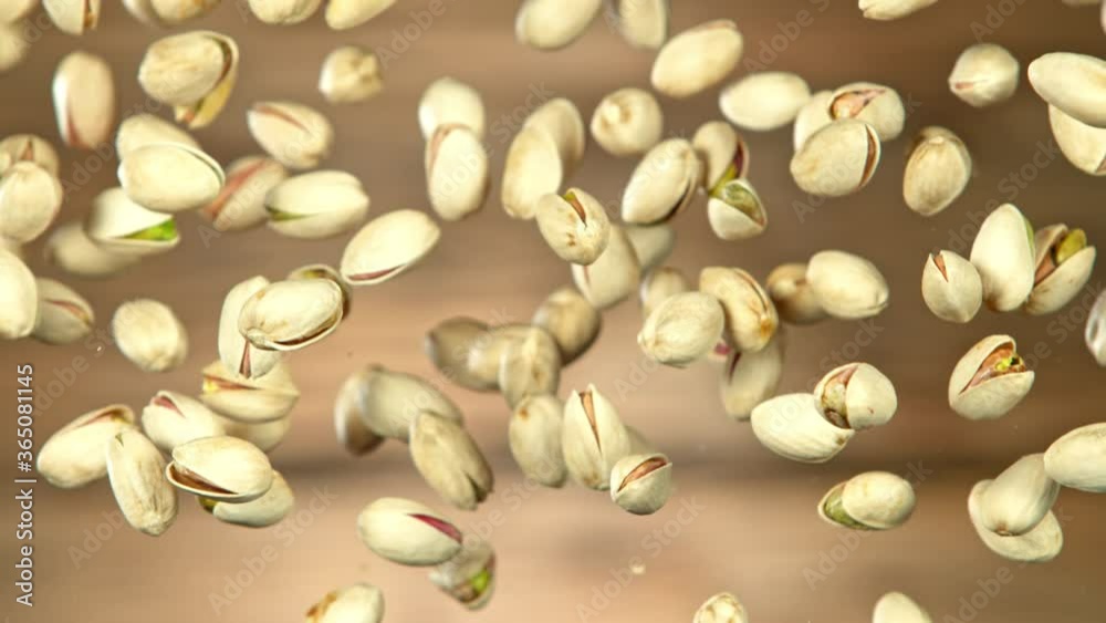 Super Slow Motion Shot of Flying Pistachios After Being Exploded on Wooden Background at 1000fps. Super Slow Motion Shot of Flying Pistachios After Being Exploded on Wooden Background at 1000fps.