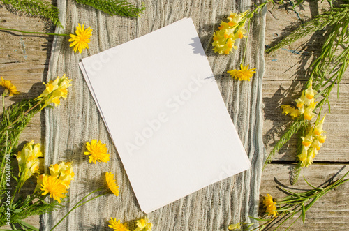 Summer stationery mockup scene with with yellow flowers on a old wood background in rustic style and natural. Mockup card for greeting card or wedding invitation. Flat lay, top