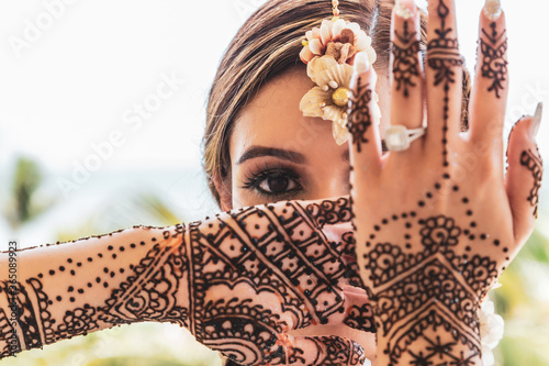 Beautiful Sikh model posing with intricate henna designs beneath bright clear skies