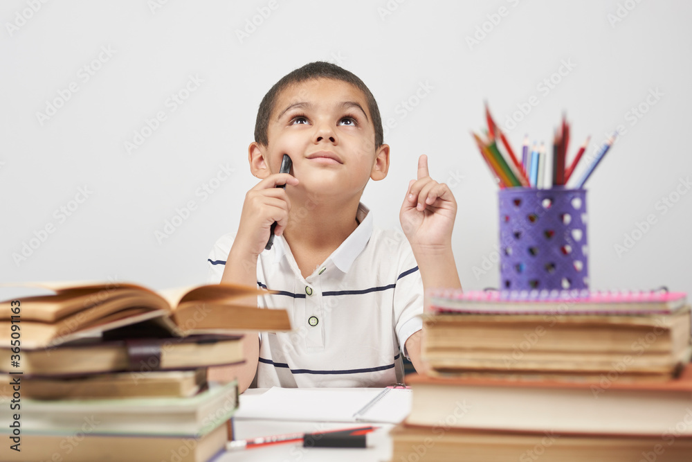 Thoughtful schoolboy having idea, raising finger. I know it. Primary school pupil thinking, creating, brainstorming, trying to make right decision