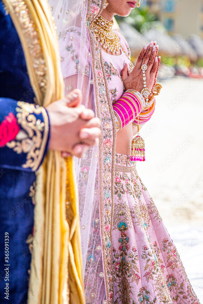 Sikh bride and groom next to each other during marriage ceremony in traditional wedding attire